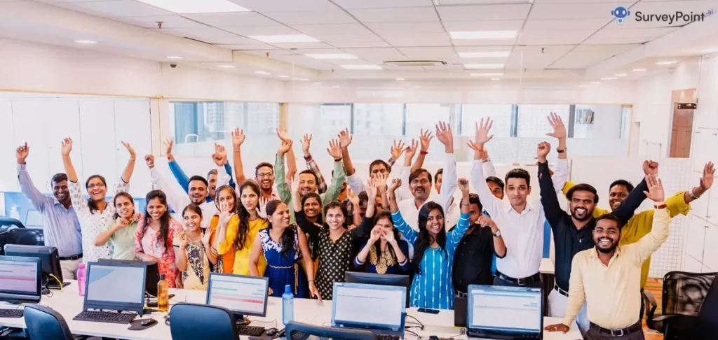 A group of people in an office raising their hands, demonstrating engagement in the workplace.