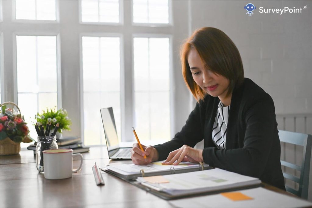 A professional woman in a business suit is writing on a piece of paper, possibly using survey tools.