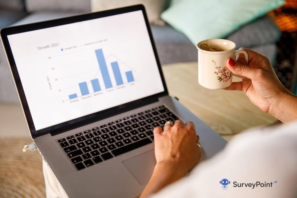 Woman holding coffee and laptop displaying bar chart on screen, related to Survey Response Rate.