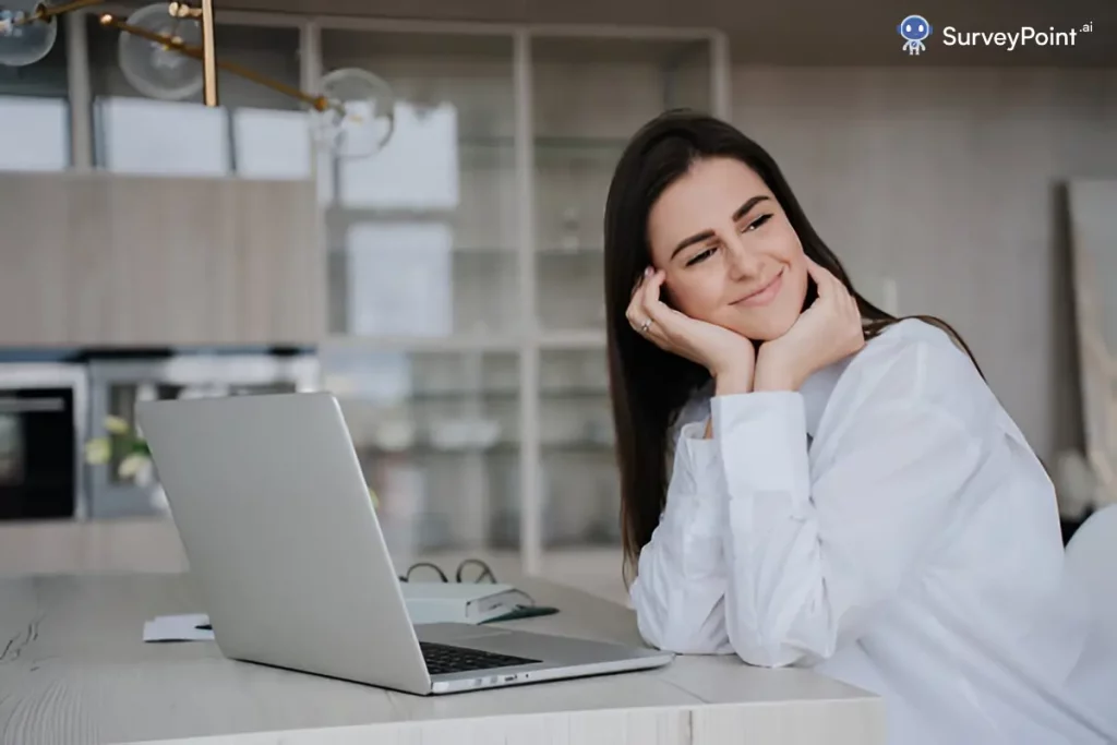 A woman seated at a table, focused on her laptop, engaged in Officevibe Surveys for workplace feedback.