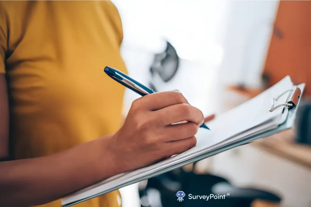 A woman actively engages in writing on a clipboard with a pen, illustrating her contribution to an Employee Engagement Survey.