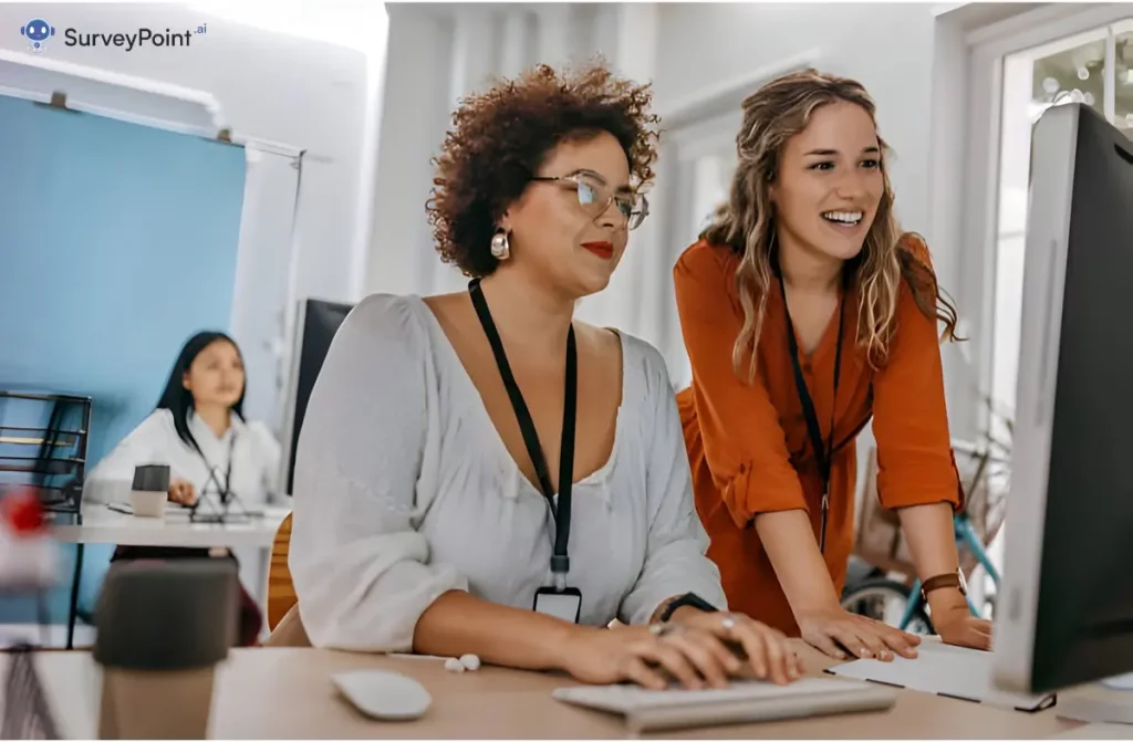 Two women collaborating on a computer in an office, focused on discussing Change Management Survey Questions.