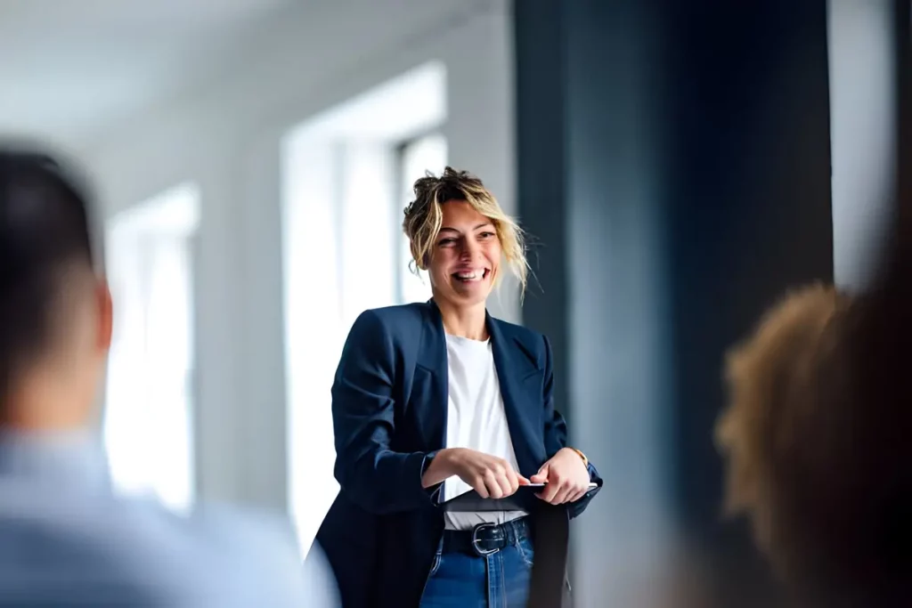 A woman presents in an office setting, discussing Phone Service Surveys with an engaged audience.