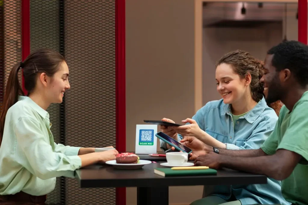 Three individuals seated at a table, engaging with a tablet while discussing inclusion survey questions.